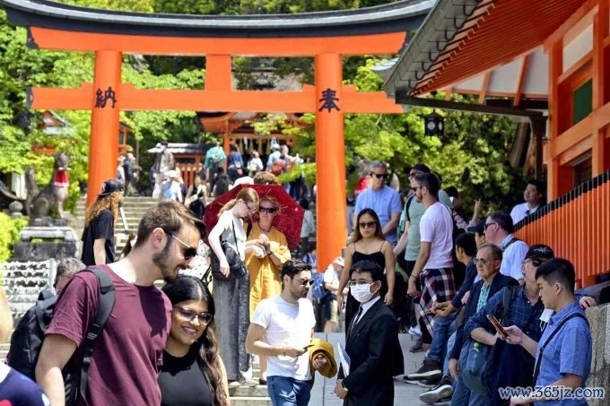 Khách nước ngoài trước cổng đền Fushimi Inari Taisha ở Kyoto tháng 4/2023. Ảnh: The Japan News